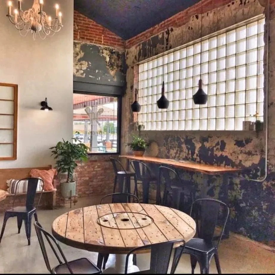 The shop interior, with brick walls, a glass-block window, and a round wood table